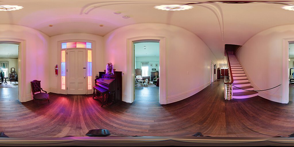 Panoramic view of the second floor door with stained glass side panels, organ and chair.