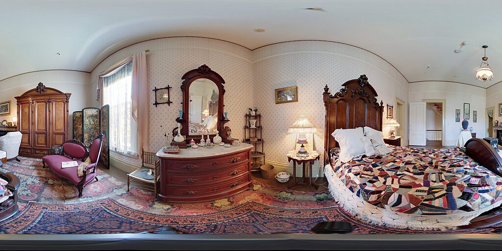 Panoramic view of the girl's room with small female mannequin, double bed, side table, pitcher, armoire and fireplace.