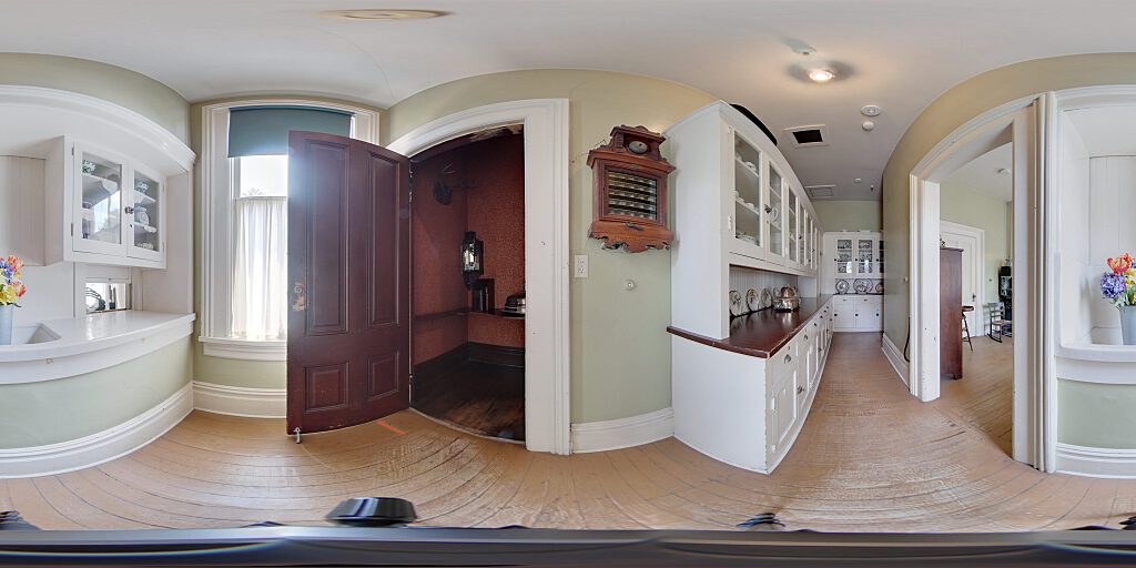 Panoramic view of the entrance to the kitchen showing Victorian Era call system next to white storage cabinets