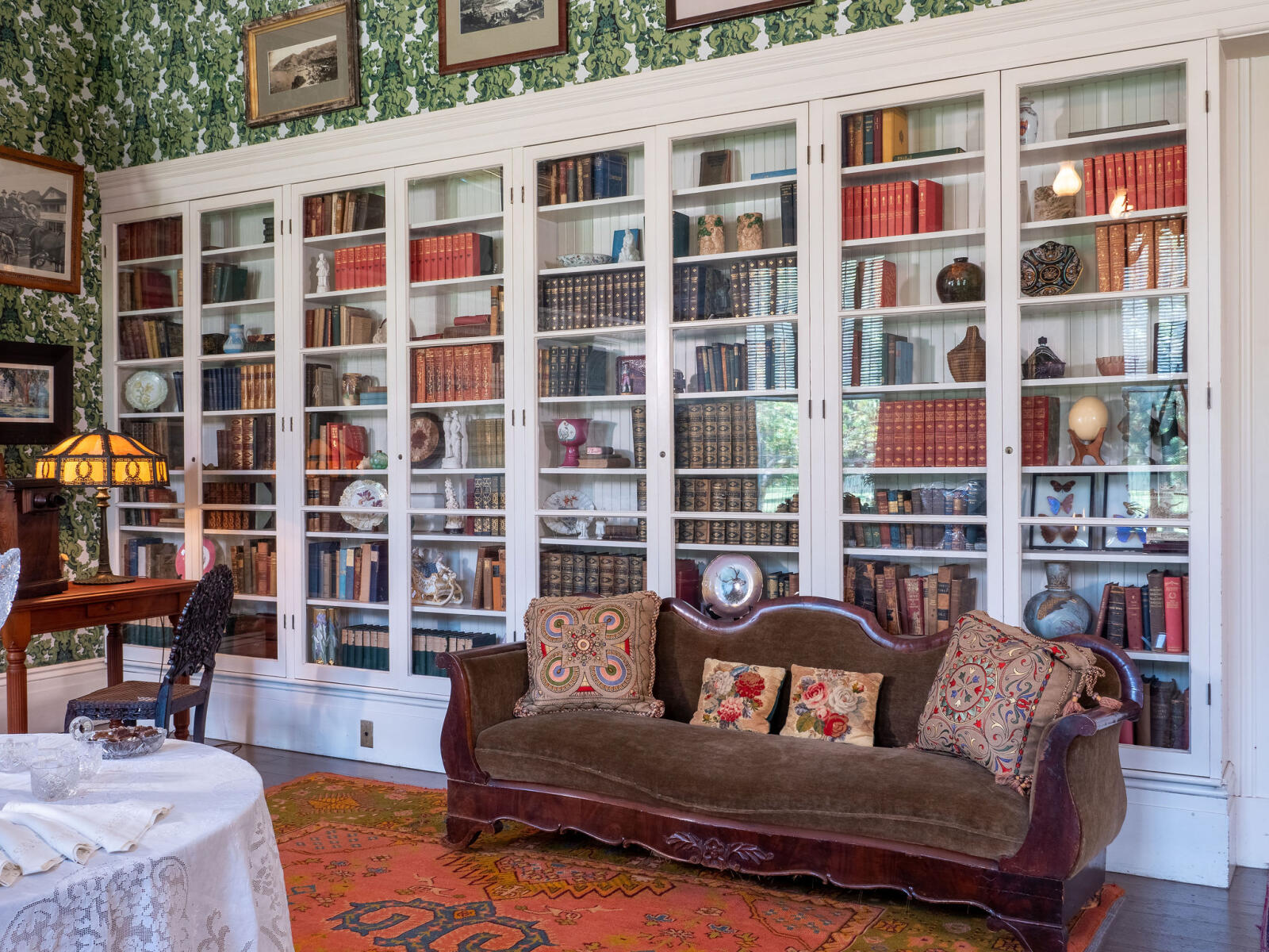 Large glass bookshelf with books and miscellaneous items and sofa