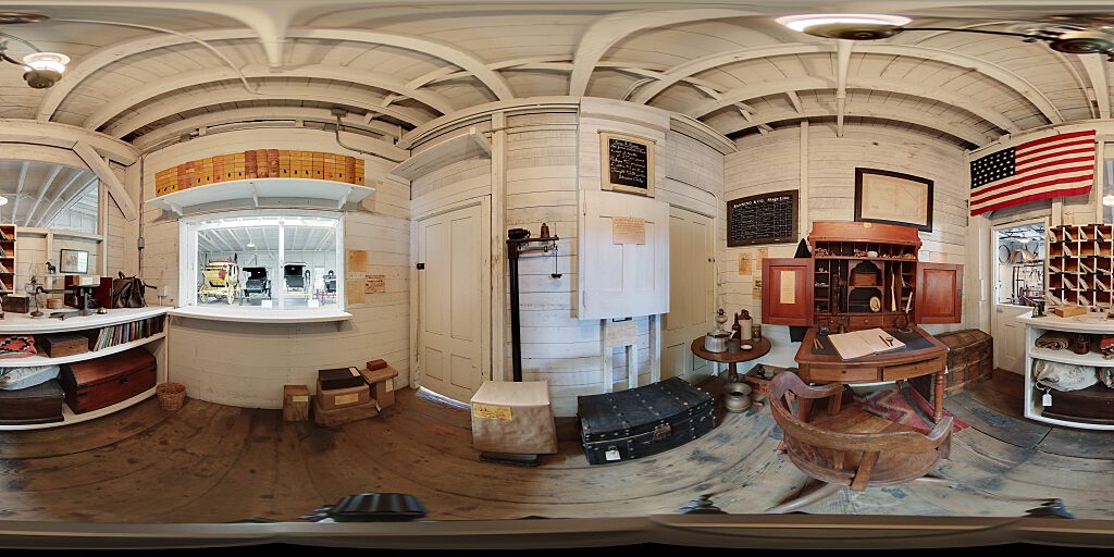 Panoramic view of Stage Coach Office with desk, American flag, mail and mail slots.