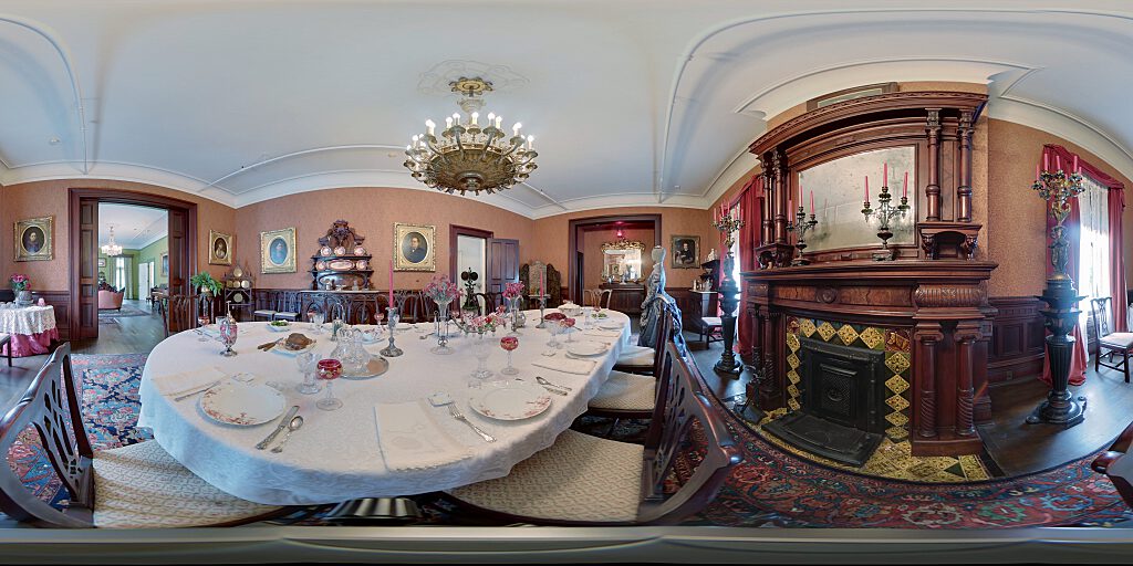 Closeup of Dining Room table set with period china and room fireplace with mirror above