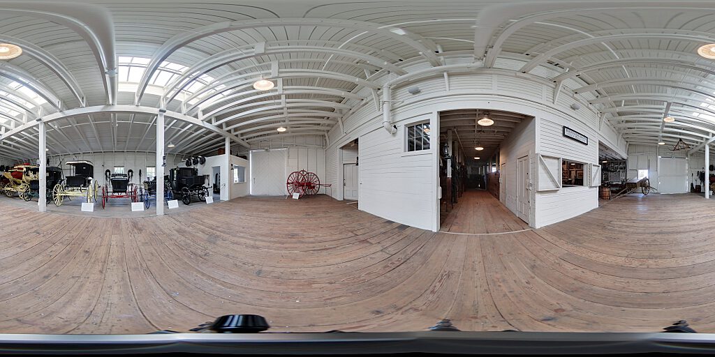 Panoramic view of Barn interior with carriages and concourse.