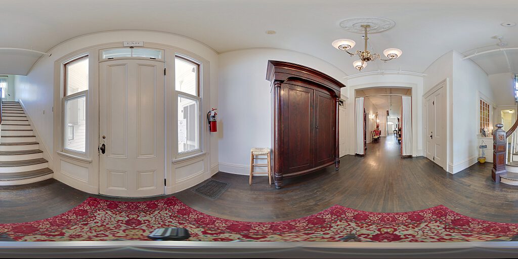 Panoramic view of backdoor with tall armoire and side staircase.