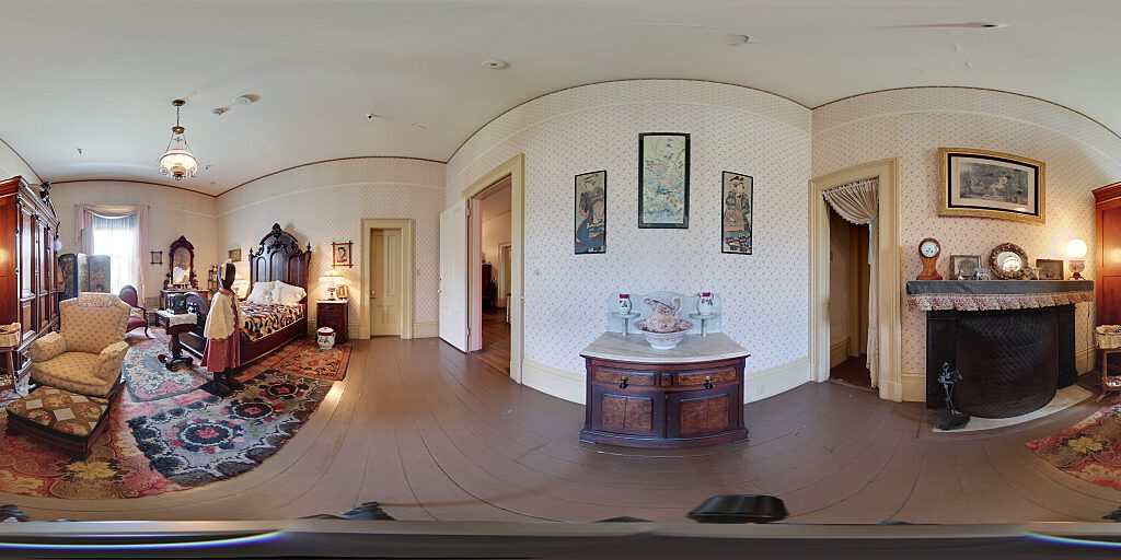Panoramic view of the girl's room with small female mannequin, double bed, side table, pitcher, armoire and fireplace.