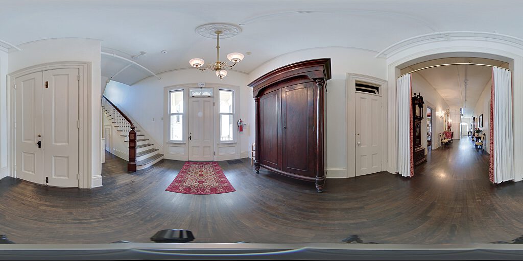 Panoramic view of backdoor with tall armoire and side staircase.