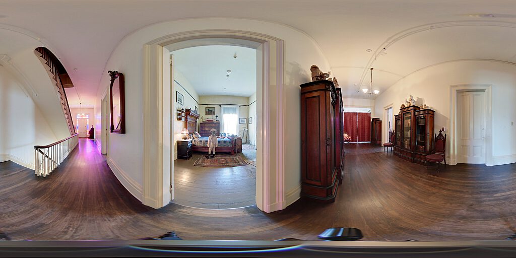 Panoramic view of the second floor door with stained glass side panels, organ and chair.