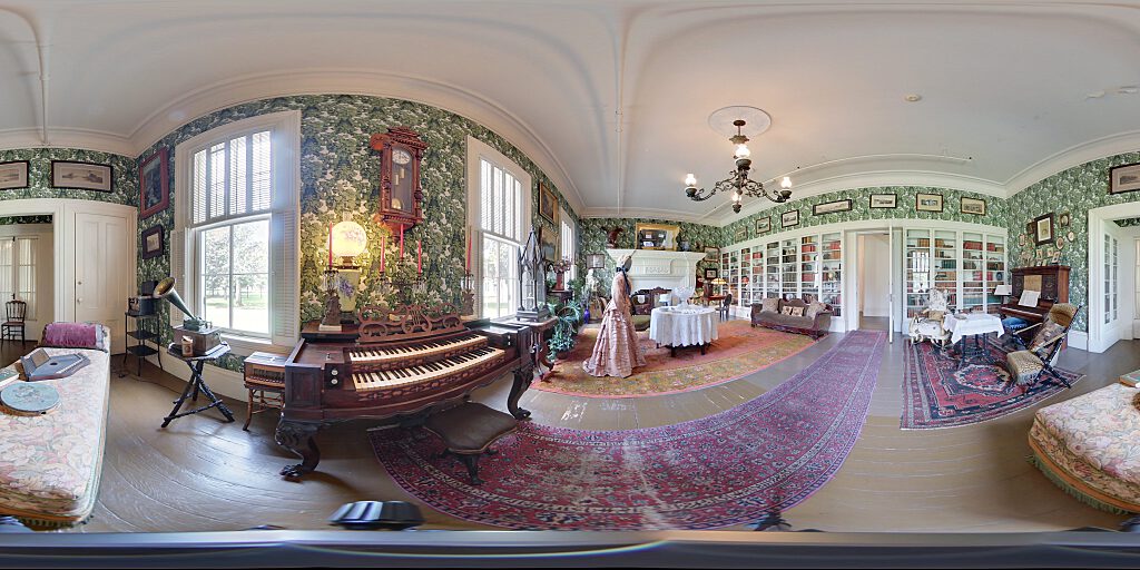 Panoramic view of Family Room with sofa, steer horn chair, table and closeup of organ and carpet